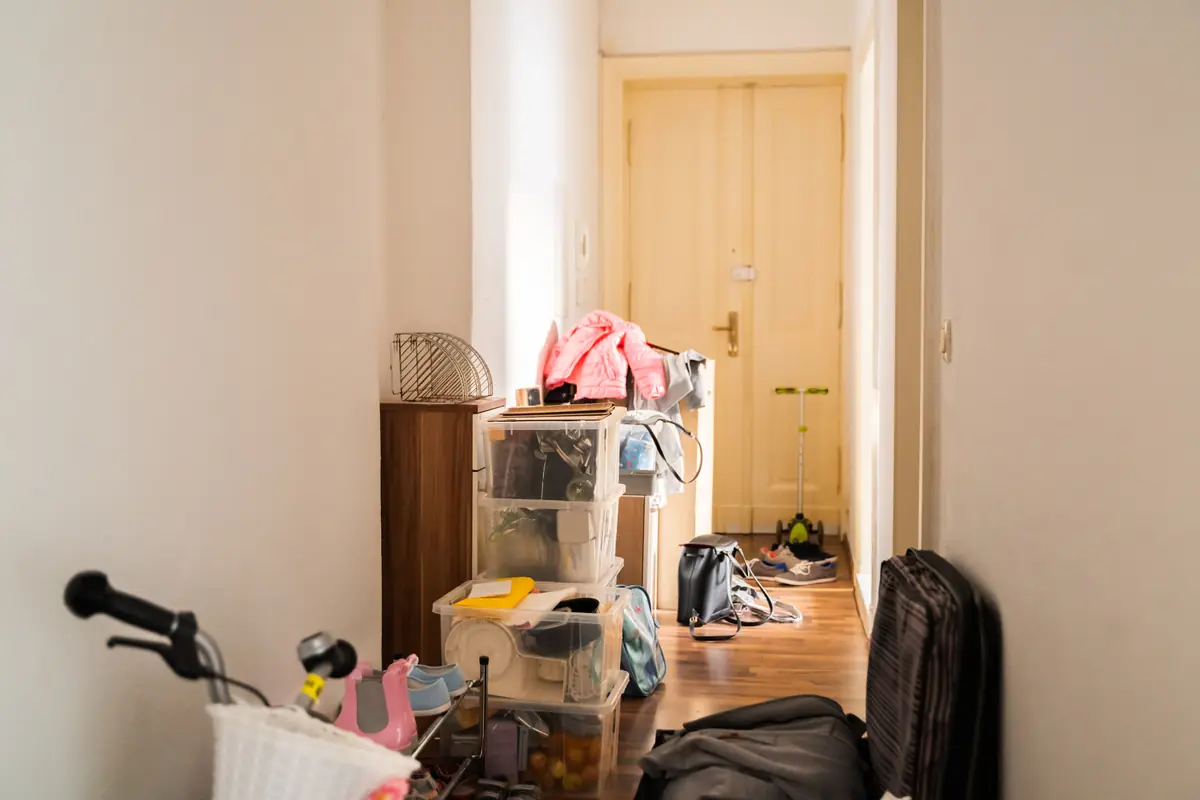 Couloir et parties communes d’un immeuble encombrés avant un débarras